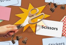 A middle schooler's hand holding scissors over its corresponding flashcard among other classroom items and flashcards.