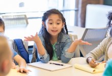 A group of elementary students in a circle engaging in a discussion while one student leads