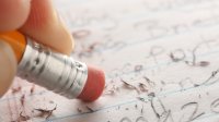 A closeup shot of a student erasing some of their work on notebook paper, representing the idea of perfectionism for teachers