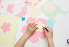 Child's hands making a paper flower creative project, representing the idea of showcasing student growth