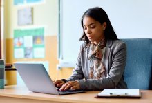 Teacher working at her desk on a laptop using AI to support PBL