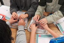 A photo of four students working together to light a lightbulb with a battery, representing supporting English learners in science classes