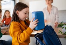 Child placing lunch box in backpack to create a no-trash lunch