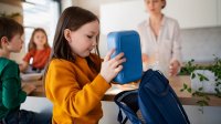 Child placing lunch box in backpack to create a no-trash lunch