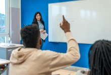 High school student raising hand during class to answer a question