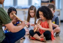 A teacher showing students how to hold a recorder