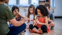 A teacher showing students how to hold a recorder