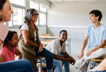 High school teacher chatting with small group of students