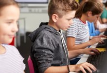 A classroom of elementary students working individually on desktop computers to recognize bias in online information