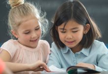 Two elementary students reading the same book together
