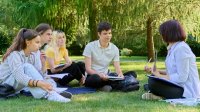 A photo of a teacher leading a lesson for high school students outdoors