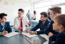 A photo of an English teacher engaged in conversation with a small group of middle school students