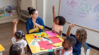 Elementary teacher works with a small group of students completing a project-based learning assignment