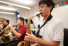 A photograph of middle school students playing brass instruments in either a music class or club.