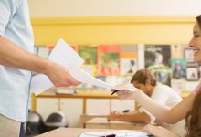 Student handing in papers to teacher