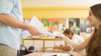 Student handing in papers to teacher