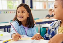 An image of two engaged elementary school students at their desks who appear excited about the work they are doing