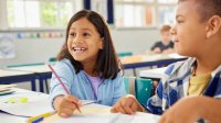 An image of two engaged elementary school students at their desks who appear excited about the work they are doing