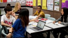 An image of a small group of middle school students collaborating on schoolwork