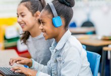 Elementary students working together at a computer making a podcast.