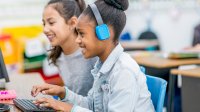 Elementary students working together at a computer making a podcast.