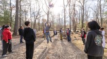students at the Greene School passing a ball in the woods