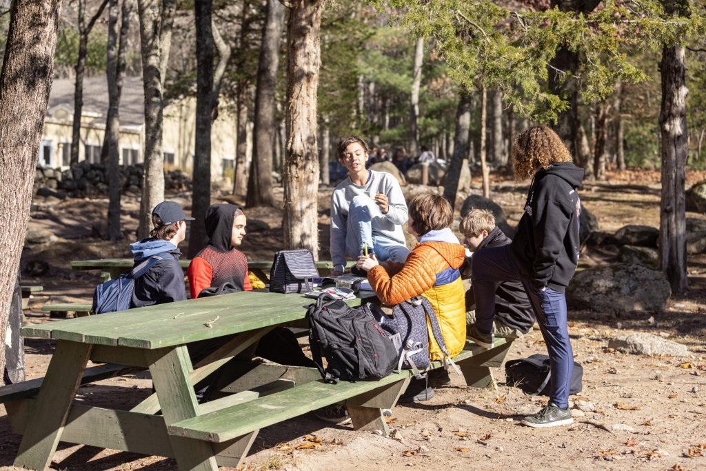 friends sit at a picnic table on school campus