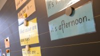 A photo of laminated cards containing English phrases attached to a board with magnets.
