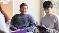 Student reading a book in a small group discussion