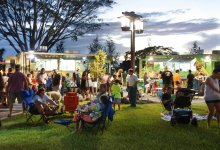 A photo of a community engaging with a row of food trucks