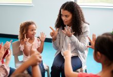 A photo of a circle of prek students following their teacher's finger counting movements.