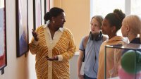 A photo of middle school students being led around an art gallery by an educator.