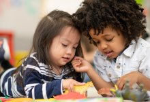 A photo of two preschool students playing with each other using toy animals.
