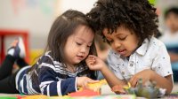 A photo of two preschool students playing with each other using toy animals.
