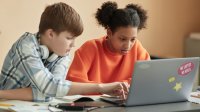 Two students working on a laptop together