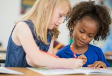 Two elementary students working with a math workbook together