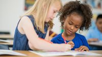 Two elementary students working with a math workbook together