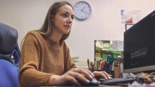 A photo of a school administrator sitting in her office looking at her desktop screen, which has the Google Gemini page pulled up.