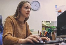 A photo of a school administrator sitting in her office looking at her desktop screen, which has the Google Gemini page pulled up.