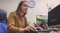 A photo of a school administrator sitting in her office looking at her desktop screen, which has the Google Gemini page pulled up.