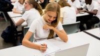 A photo of a middle school student having an "aha" moment while completing schoolwork at her desk.