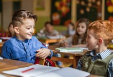 A photo focusing on two elementary students talking through group work at their desks.