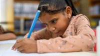A photo of a first grade student diligently working on a writing assignment.