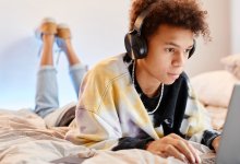 Teenager working on a laptop and listening to music