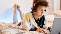 Teenager working on a laptop and listening to music
