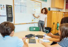 A photo of middle school students attentively taking notes as their teacher explains mathematical concepts at the whiteboard.