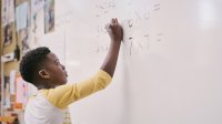 A photo of an elementary student solving square multiplication problems on the class whiteboard.