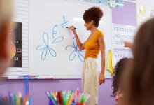 A photo of an elementary teacher drawing flower petals to demonstrate fractions on a whiteboard.