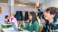 Engaged middle school classroom with student raising his hand