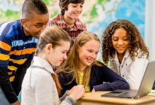 A photo of middle school students in a social studies classroom doing group work on a computer.